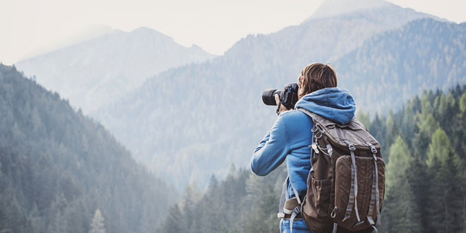 Um homem a tirar uma fotografia de uma cena de paisagem de montanha
